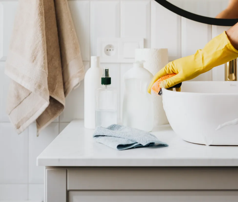 A person in yellow gloves is washing dishes.