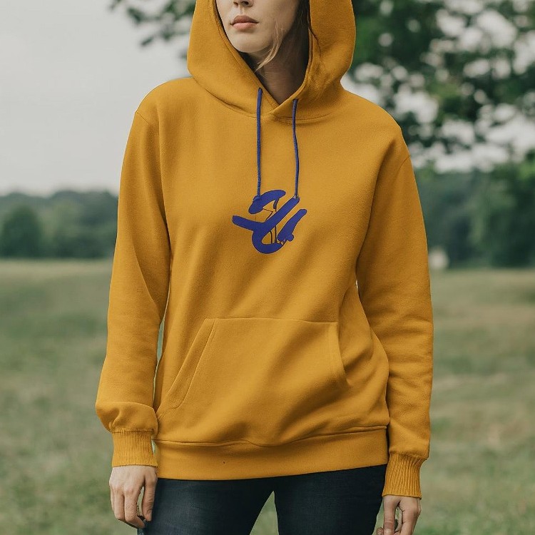 A person wearing a yellow hoodie standing in the grass.