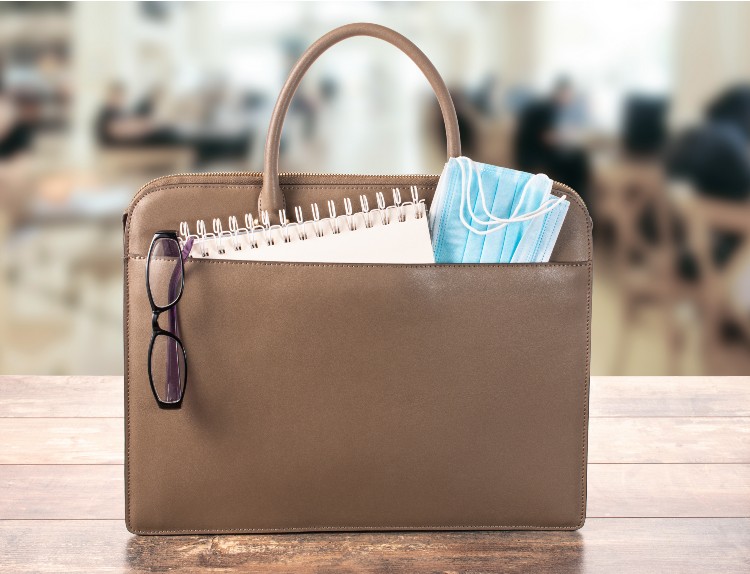 A brown purse with some papers and glasses in it